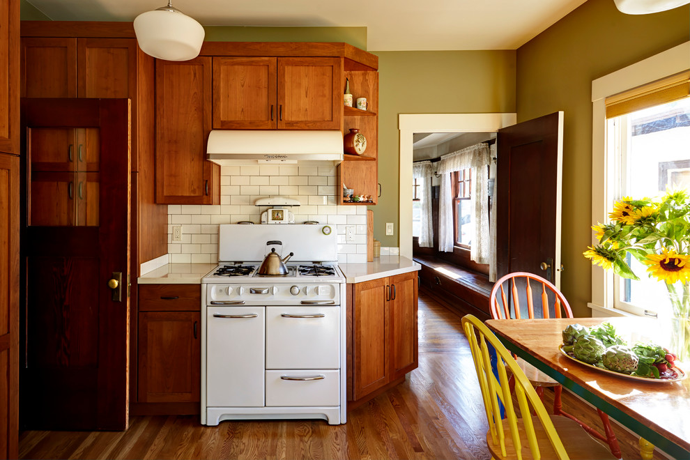 This is an example of a medium sized classic enclosed kitchen in San Francisco with a submerged sink, shaker cabinets, medium wood cabinets, engineered stone countertops, white splashback, ceramic splashback, white appliances and medium hardwood flooring.