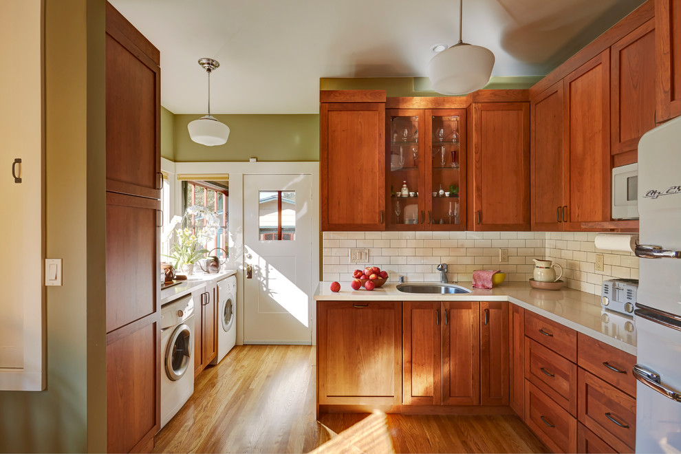 Photo of a medium sized traditional l-shaped enclosed kitchen in San Francisco with a submerged sink, shaker cabinets, medium wood cabinets, engineered stone countertops, white splashback, ceramic splashback, white appliances and medium hardwood flooring.