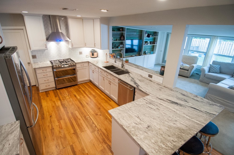 Eat-in kitchen - large traditional u-shaped medium tone wood floor and multicolored floor eat-in kitchen idea in Austin with a triple-bowl sink, shaker cabinets, white cabinets, granite countertops, white backsplash, subway tile backsplash, stainless steel appliances and a peninsula