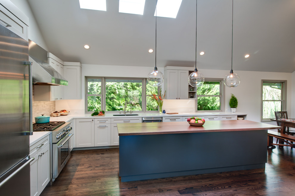 This is an example of a large classic l-shaped open plan kitchen in San Francisco with a submerged sink, stainless steel appliances, dark hardwood flooring, shaker cabinets, white cabinets, composite countertops, beige splashback, stone tiled splashback and an island.