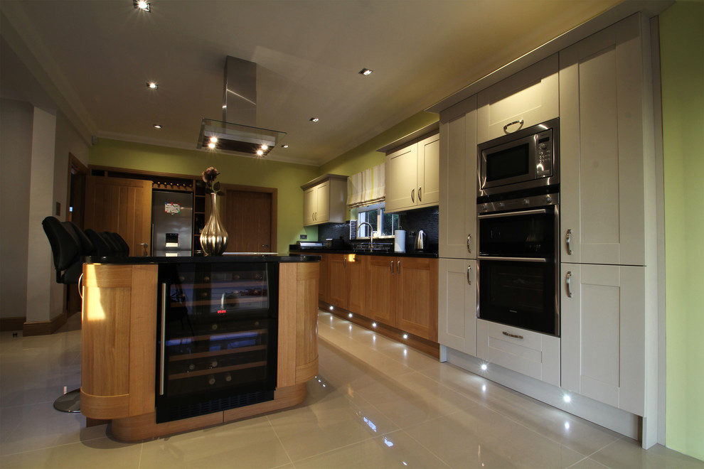 Bild på ett stort funkis linjärt kök och matrum, med en undermonterad diskho, skåp i shakerstil, skåp i mellenmörkt trä, granitbänkskiva, blått stänkskydd, stänkskydd i mosaik, svarta vitvaror, klinkergolv i porslin, en köksö och vitt golv