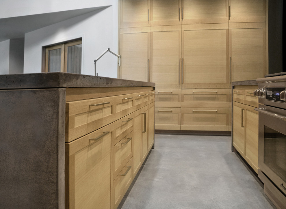 Inspiration for a large modern galley concrete floor open concept kitchen remodel in Chicago with an undermount sink, shaker cabinets, light wood cabinets, concrete countertops, paneled appliances and two islands