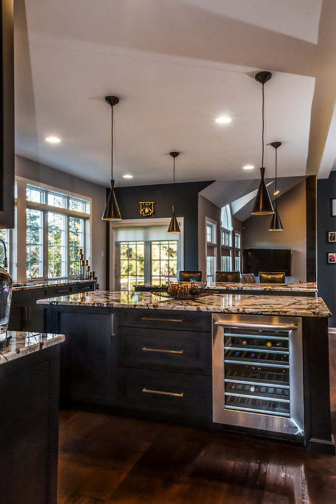 Foto på ett stort funkis flerfärgad kök, med en undermonterad diskho, skåp i shakerstil, svarta skåp, granitbänkskiva, grått stänkskydd, stänkskydd i porslinskakel, rostfria vitvaror, mellanmörkt trägolv, flera köksöar och brunt golv