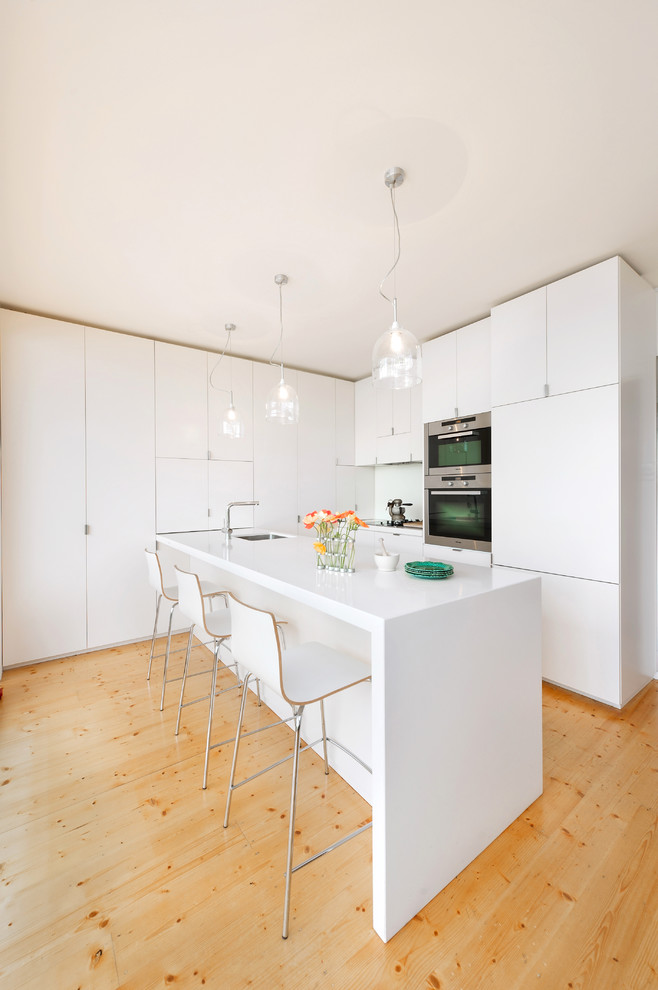 メルボルンにあるコンテンポラリースタイルのおしゃれなL型キッチン (フラットパネル扉のキャビネット、白いキャビネット、シルバーの調理設備) の写真