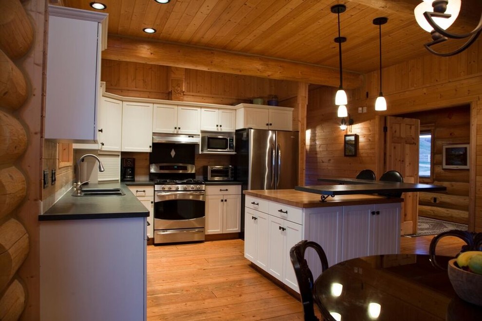Immagine di una cucina stile rurale di medie dimensioni con ante in stile shaker, elettrodomestici in acciaio inossidabile e pavimento in legno massello medio