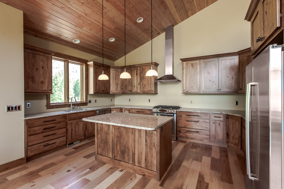 Rustic u-shaped kitchen/diner in Other with a submerged sink, recessed-panel cabinets, medium wood cabinets, wood worktops, stainless steel appliances, light hardwood flooring and an island.