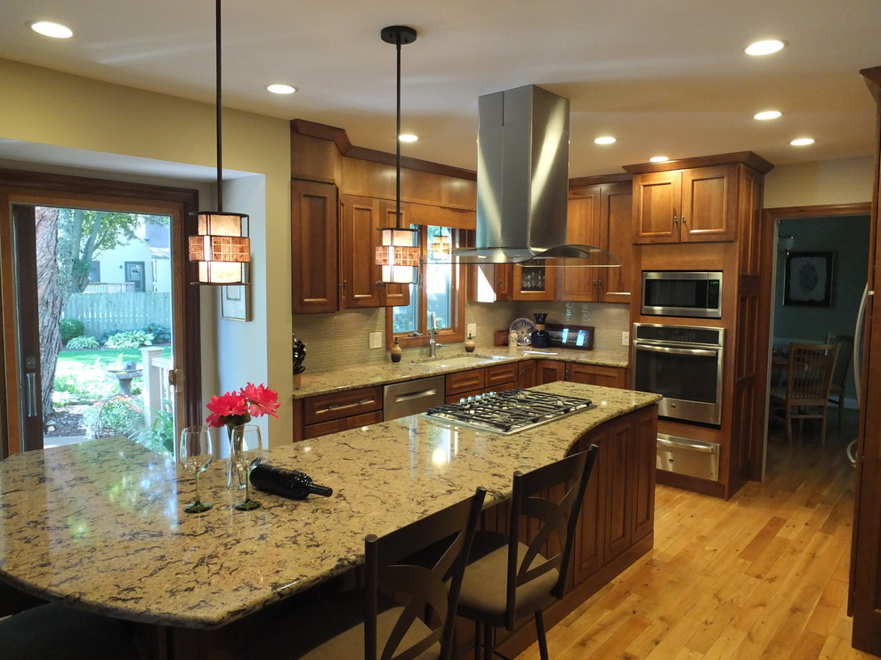 Inspiration for a mid-sized u-shaped light wood floor enclosed kitchen remodel in Columbus with an undermount sink, shaker cabinets, medium tone wood cabinets, quartz countertops, black backsplash, glass sheet backsplash, stainless steel appliances and an island