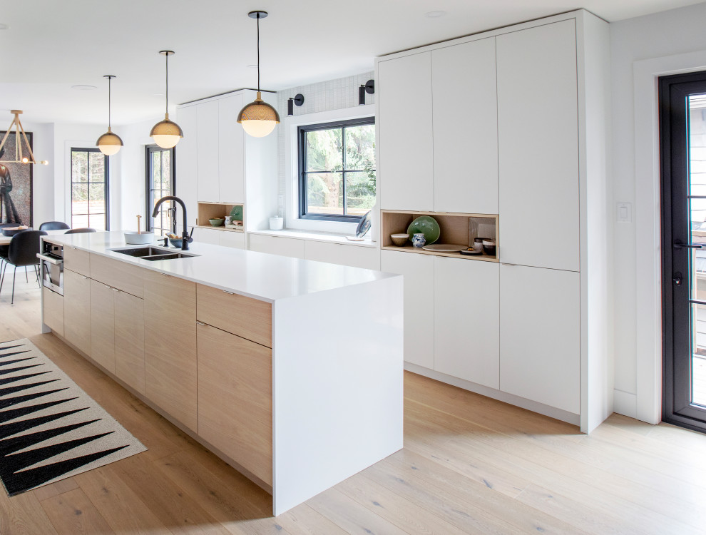 Diseño de cocina contemporánea con fregadero bajoencimera, armarios con paneles lisos, puertas de armario blancas, suelo de madera clara, una isla, suelo beige y encimeras blancas