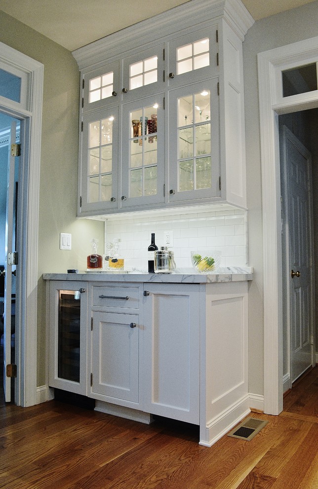 Klassisk inredning av ett stort kök, med skåp i shakerstil, vita skåp, marmorbänkskiva, vitt stänkskydd, stänkskydd i tunnelbanekakel, rostfria vitvaror, ljust trägolv och en köksö