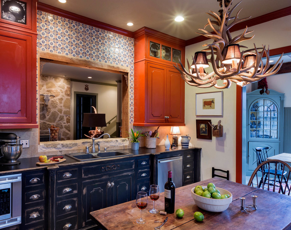 Inspiration for a mid-sized cottage u-shaped medium tone wood floor kitchen remodel in Dallas with a double-bowl sink, raised-panel cabinets, distressed cabinets, wood countertops, multicolored backsplash, terra-cotta backsplash and stainless steel appliances