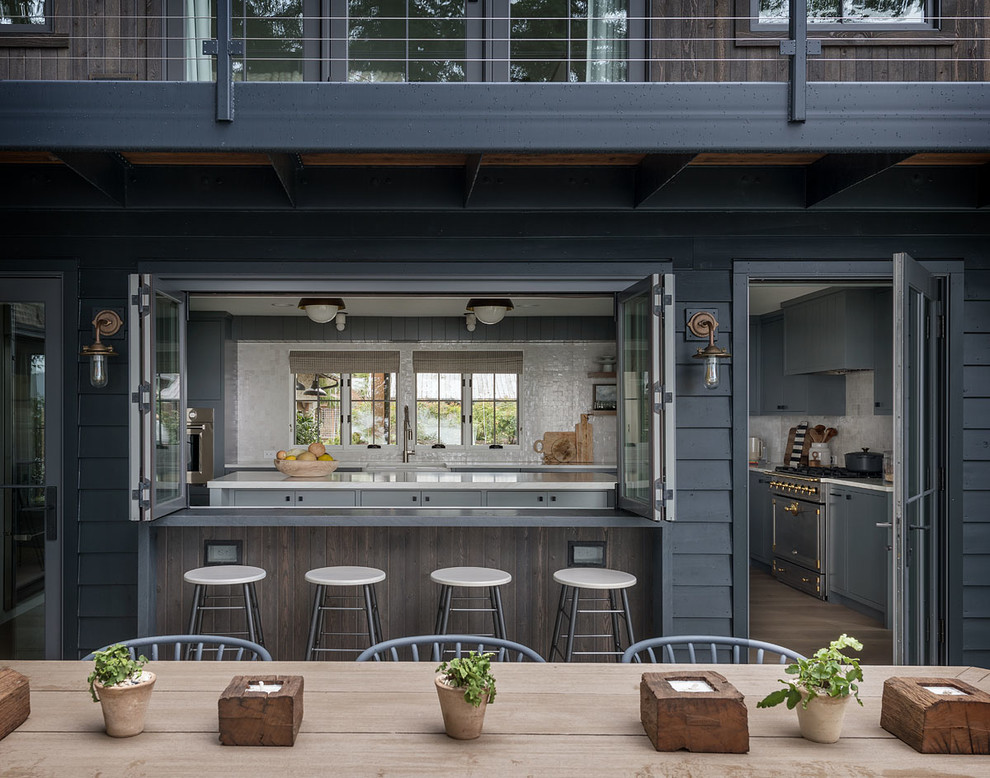 Example of a country kitchen design in Seattle with a farmhouse sink, stainless steel appliances and an island