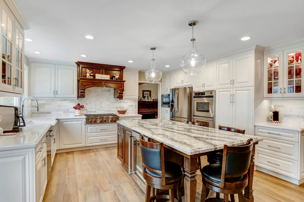 Exempel på ett mellanstort klassiskt vit vitt kök, med en rustik diskho, luckor med upphöjd panel, vita skåp, bänkskiva i kvarts, vitt stänkskydd, stänkskydd i marmor, rostfria vitvaror, klinkergolv i porslin, en köksö och brunt golv