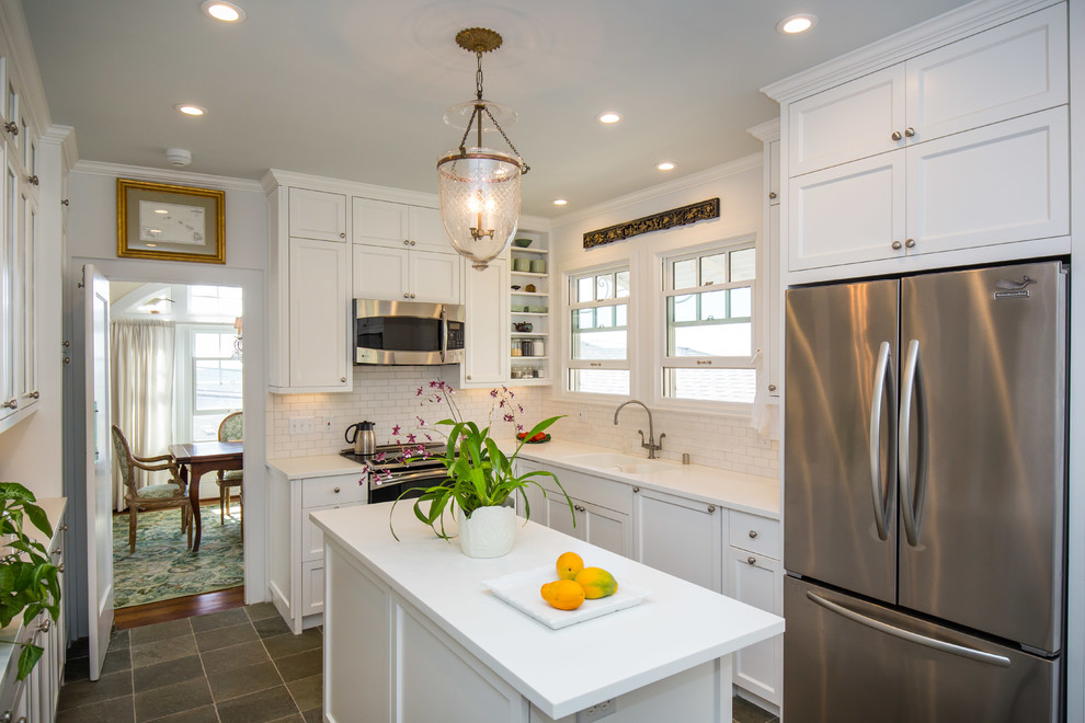 Example of a classic u-shaped kitchen pantry design in Hawaii with a double-bowl sink, shaker cabinets, white cabinets, white backsplash, stainless steel appliances, an island and subway tile backsplash