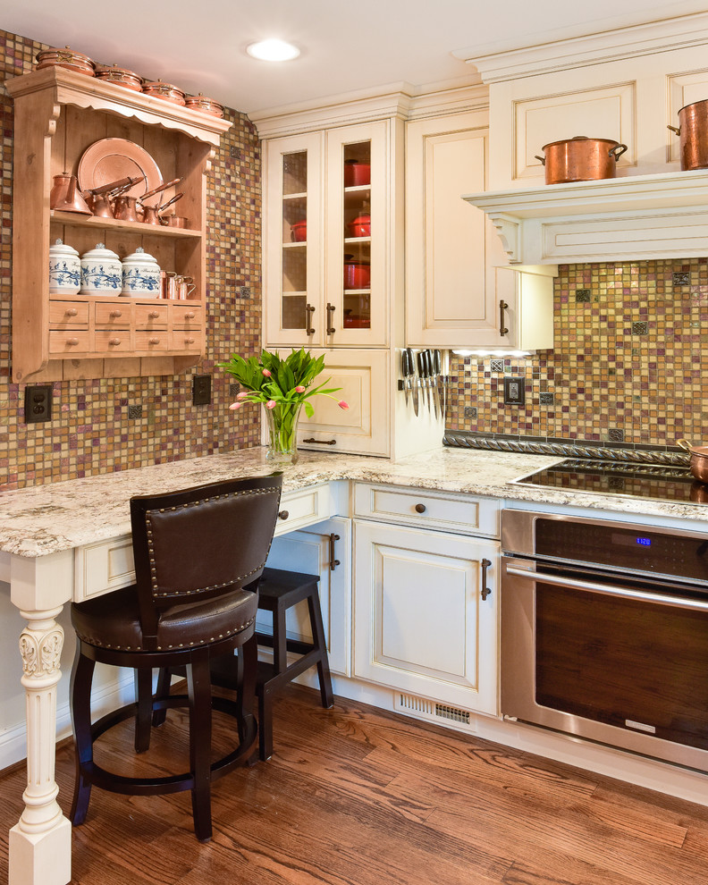 Idéer för ett mellanstort klassiskt u-kök, med en undermonterad diskho, luckor med upphöjd panel, vita skåp, granitbänkskiva, flerfärgad stänkskydd, stänkskydd i mosaik, integrerade vitvaror, mellanmörkt trägolv, en halv köksö och brunt golv