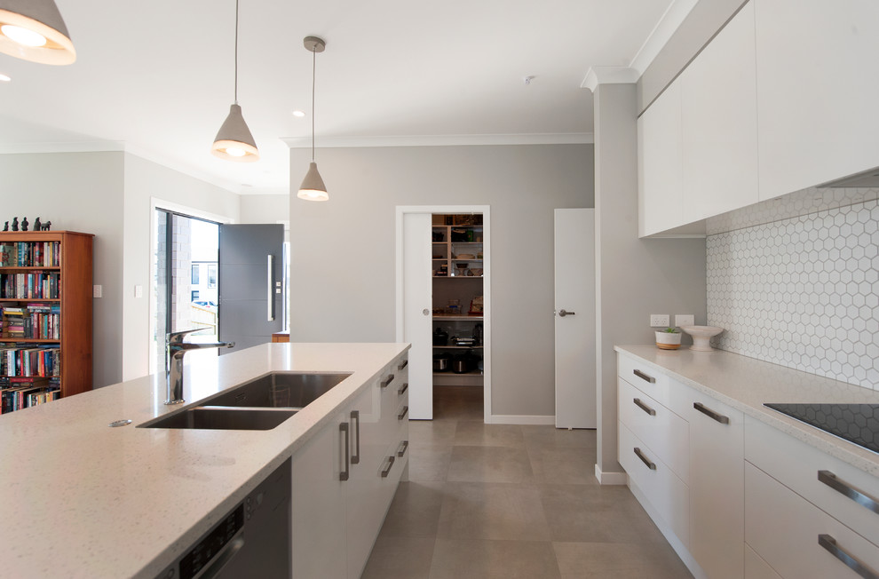 Inspiration for a medium sized modern l-shaped kitchen/diner in Auckland with a double-bowl sink, recessed-panel cabinets, white cabinets, granite worktops, white splashback, ceramic splashback, stainless steel appliances, ceramic flooring, an island, grey floors and white worktops.
