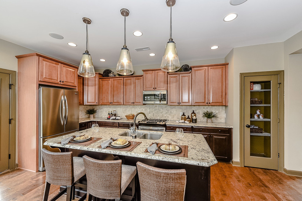Inspiration for a small timeless l-shaped light wood floor open concept kitchen remodel in Charlotte with a double-bowl sink, raised-panel cabinets, granite countertops, multicolored backsplash, mosaic tile backsplash, stainless steel appliances, an island and medium tone wood cabinets