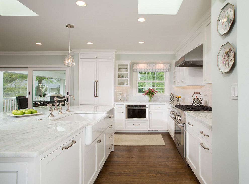 Inspiration for a traditional l-shaped open plan kitchen in DC Metro with a belfast sink, recessed-panel cabinets, white cabinets, marble worktops, white splashback, an island and grey worktops.