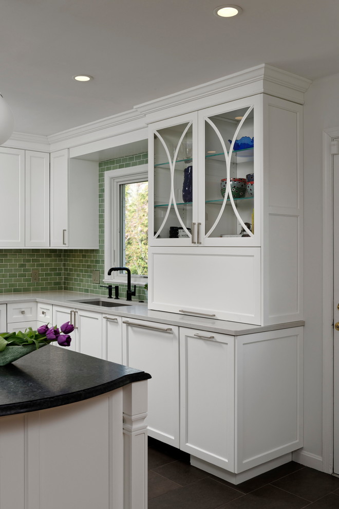 Bild på ett avskilt, mellanstort vintage vit vitt u-kök, med en enkel diskho, släta luckor, vita skåp, bänkskiva i kvarts, grönt stänkskydd, stänkskydd i keramik, rostfria vitvaror, klinkergolv i porslin, en köksö och brunt golv