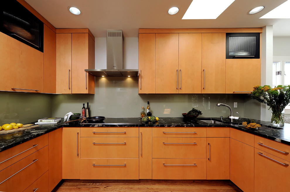 ワシントンD.C.にある高級な中くらいなコンテンポラリースタイルのおしゃれなキッチン (ダブルシンク、フラットパネル扉のキャビネット、中間色木目調キャビネット、御影石カウンター、シルバーの調理設備、淡色無垢フローリング、アイランドなし、緑のキッチンパネル、ガラス板のキッチンパネル、ベージュの床) の写真