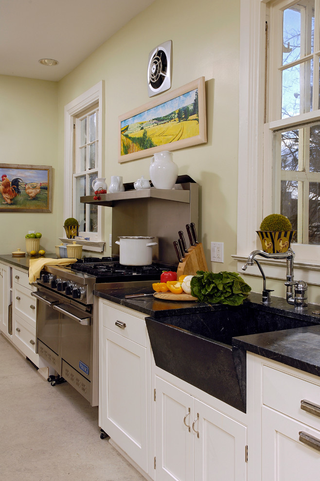 Bild på ett mellanstort lantligt kök, med en undermonterad diskho, skåp i shakerstil, vita skåp, granitbänkskiva, rostfria vitvaror, en köksö, betonggolv, grönt stänkskydd, fönster som stänkskydd och beiget golv