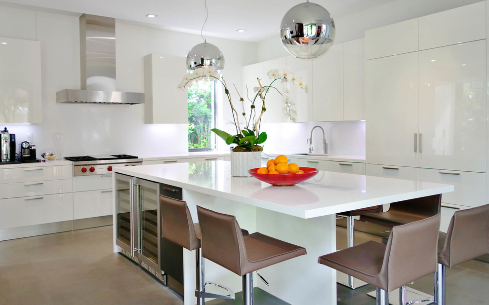 Moderne Küche in L-Form mit flächenbündigen Schrankfronten, weißen Schränken, Küchenrückwand in Weiß und Elektrogeräten mit Frontblende in Miami