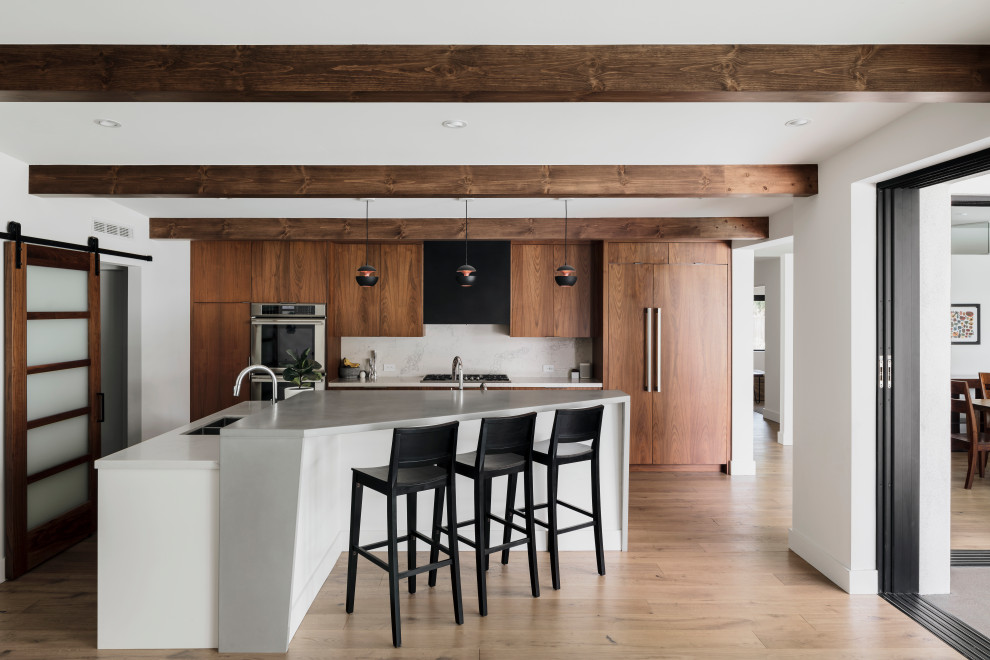 1960s single-wall medium tone wood floor and exposed beam open concept kitchen photo in Phoenix with flat-panel cabinets, dark wood cabinets, concrete countertops, quartz backsplash and an island