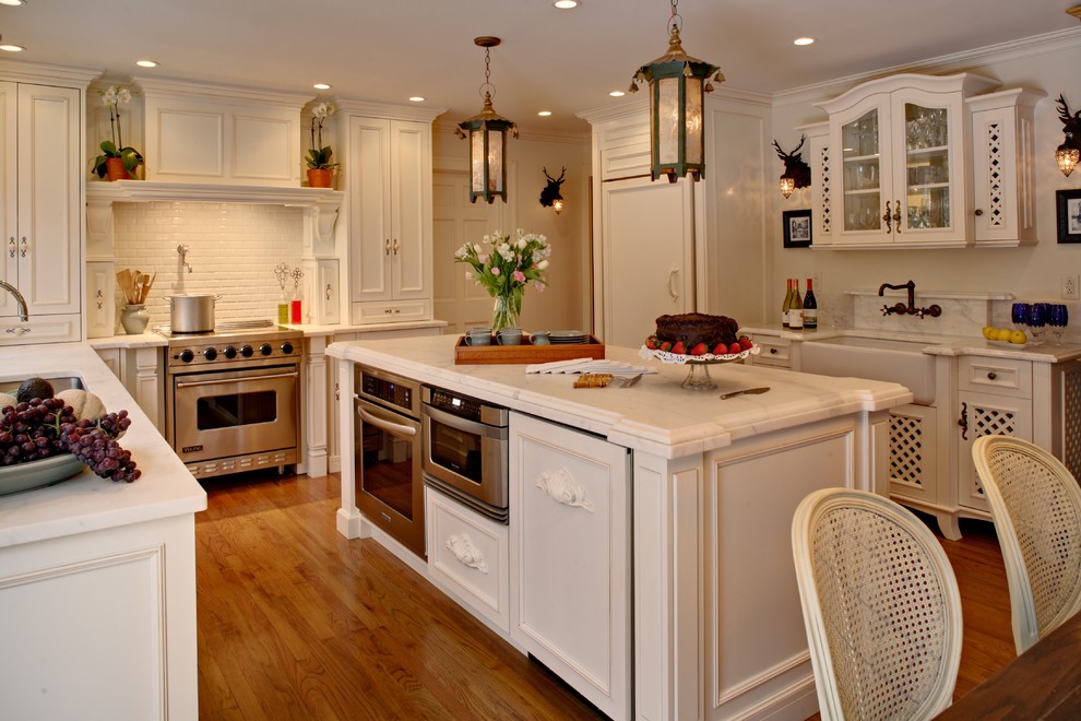 Inspiration for a french country u-shaped kitchen remodel in New York with recessed-panel cabinets, paneled appliances, subway tile backsplash, a farmhouse sink, white cabinets, marble countertops and white backsplash