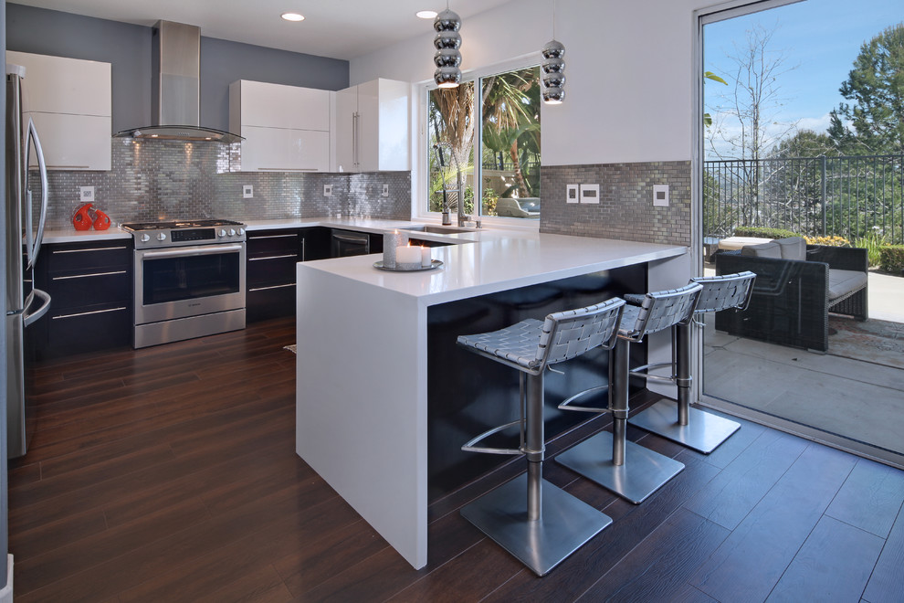 Inspiration for a mid-sized contemporary dark wood floor eat-in kitchen remodel in Orange County with a single-bowl sink, flat-panel cabinets, white cabinets, quartz countertops, metallic backsplash, metal backsplash, stainless steel appliances and a peninsula