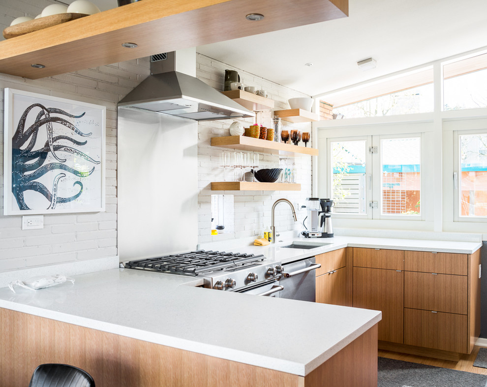 Inspiration for a retro u-shaped kitchen in Seattle with a submerged sink, flat-panel cabinets, light wood cabinets, metallic splashback, stainless steel appliances and a breakfast bar.