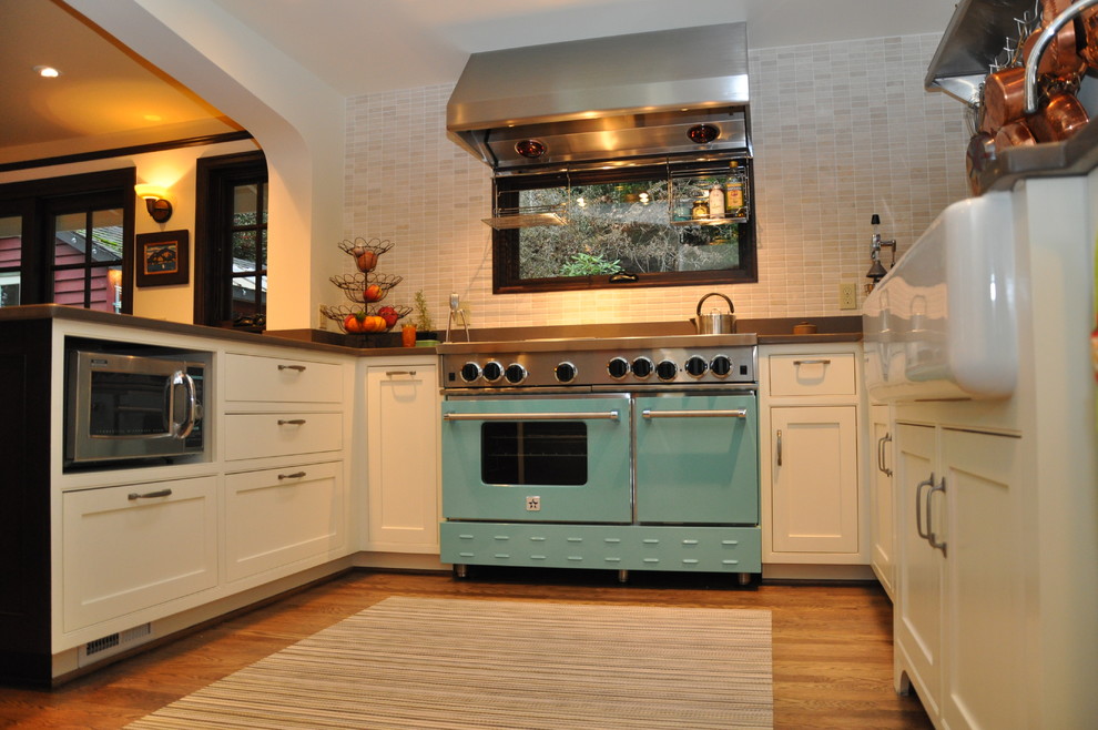 Inredning av ett klassiskt kök, med en rustik diskho, vita skåp, grått stänkskydd, stänkskydd i stenkakel, färgglada vitvaror, bänkskiva i kvarts och luckor med profilerade fronter