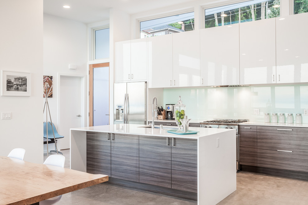 Zweizeilige Moderne Küche mit flächenbündigen Schrankfronten, grauen Schränken, Küchenrückwand in Weiß, Glasrückwand, Küchengeräten aus Edelstahl und Kücheninsel in Seattle