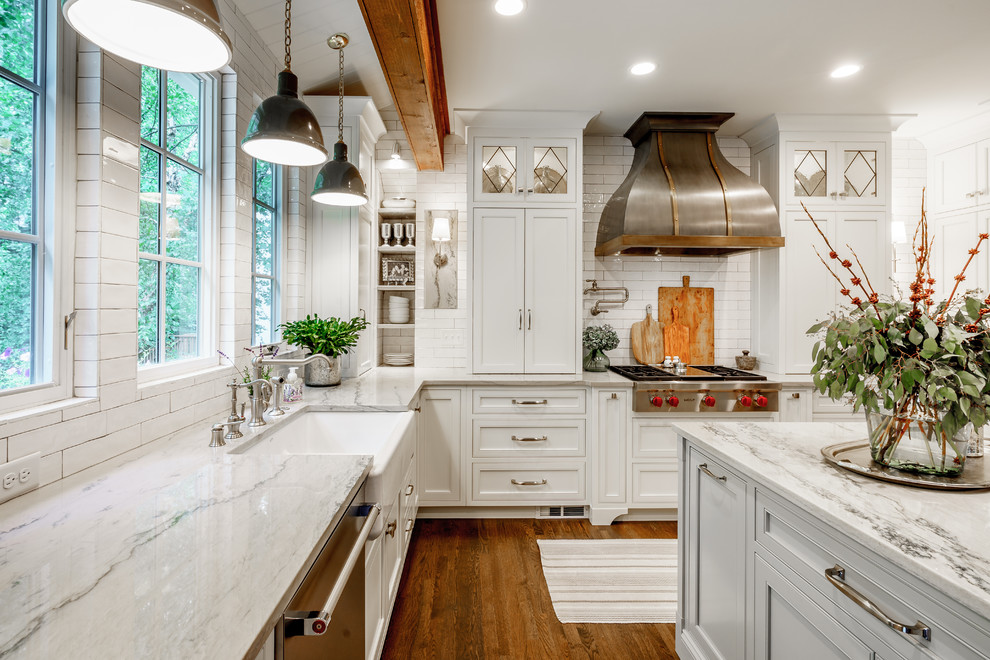 Inspiration for a mid-sized cottage u-shaped dark wood floor and brown floor eat-in kitchen remodel in Atlanta with white cabinets, quartzite countertops, white backsplash, an island, a farmhouse sink, subway tile backsplash, stainless steel appliances, shaker cabinets and white countertops
