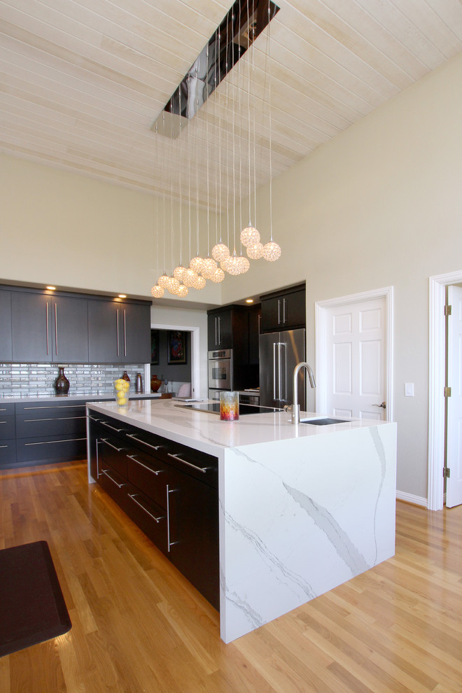 Example of a large minimalist u-shaped light wood floor and brown floor eat-in kitchen design in San Francisco with an undermount sink, flat-panel cabinets, dark wood cabinets, quartz countertops, gray backsplash, glass tile backsplash, stainless steel appliances, an island and white countertops