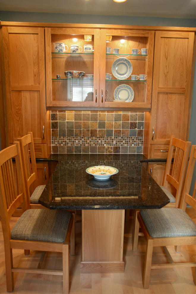 Bild på ett amerikanskt kök, med en undermonterad diskho, skåp i shakerstil, skåp i mellenmörkt trä, granitbänkskiva, rostfria vitvaror och ljust trägolv