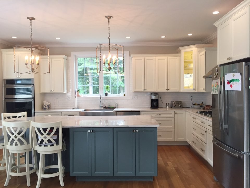 Eat-in kitchen - large farmhouse l-shaped dark wood floor and brown floor eat-in kitchen idea in Boston with a farmhouse sink, recessed-panel cabinets, white cabinets, marble countertops, white backsplash, subway tile backsplash, stainless steel appliances and an island
