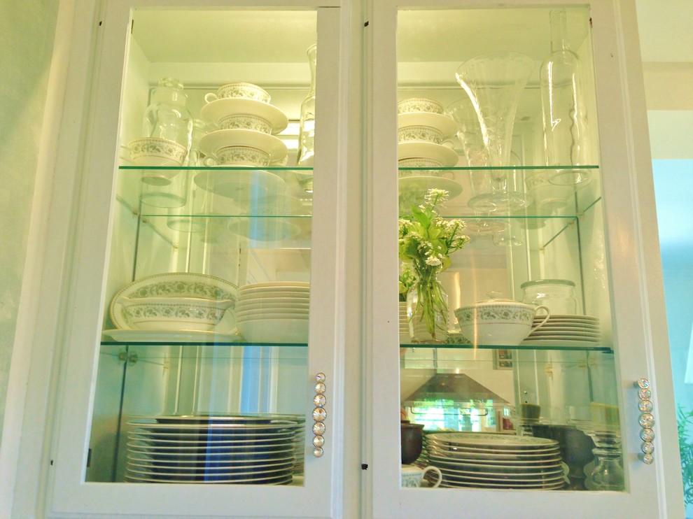 Geschlossene Klassische Küche in U-Form mit integriertem Waschbecken, Glasfronten, blauen Schränken, Arbeitsplatte aus Holz, Küchenrückwand in Weiß, Küchengeräten aus Edelstahl, gebeiztem Holzboden und Rückwand aus Spiegelfliesen in Sonstige