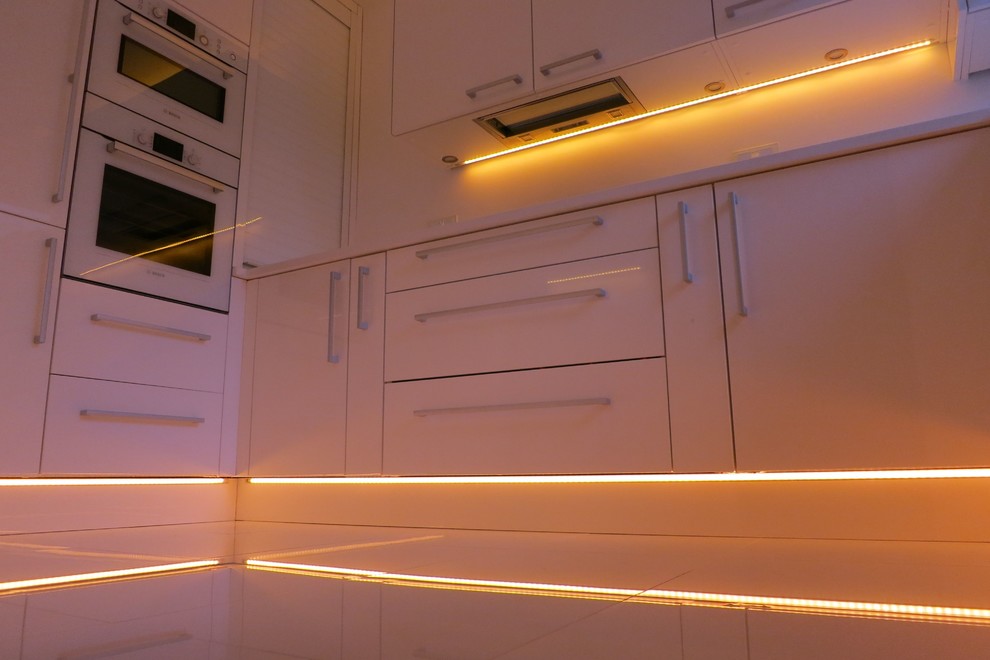 Immagine di una piccola cucina ad U moderna chiusa con lavello sottopiano, ante lisce, ante bianche, top in quarzite, paraspruzzi bianco, paraspruzzi con lastra di vetro, elettrodomestici bianchi, pavimento con piastrelle in ceramica e nessuna isola