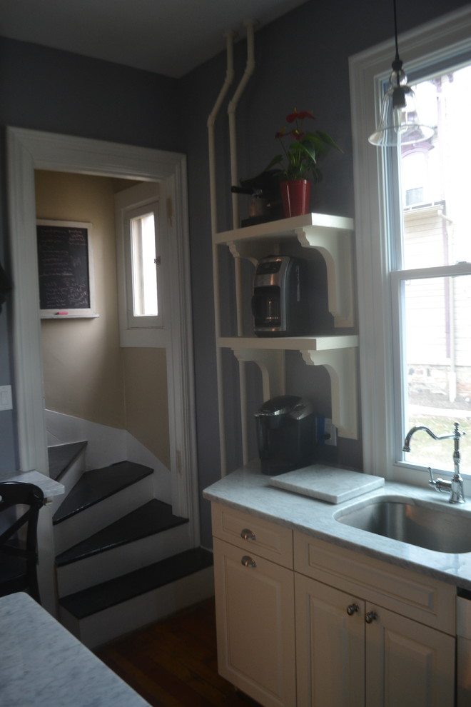 Immagine di una piccola cucina vittoriana chiusa con lavello sottopiano, ante con bugna sagomata, ante bianche e top in marmo