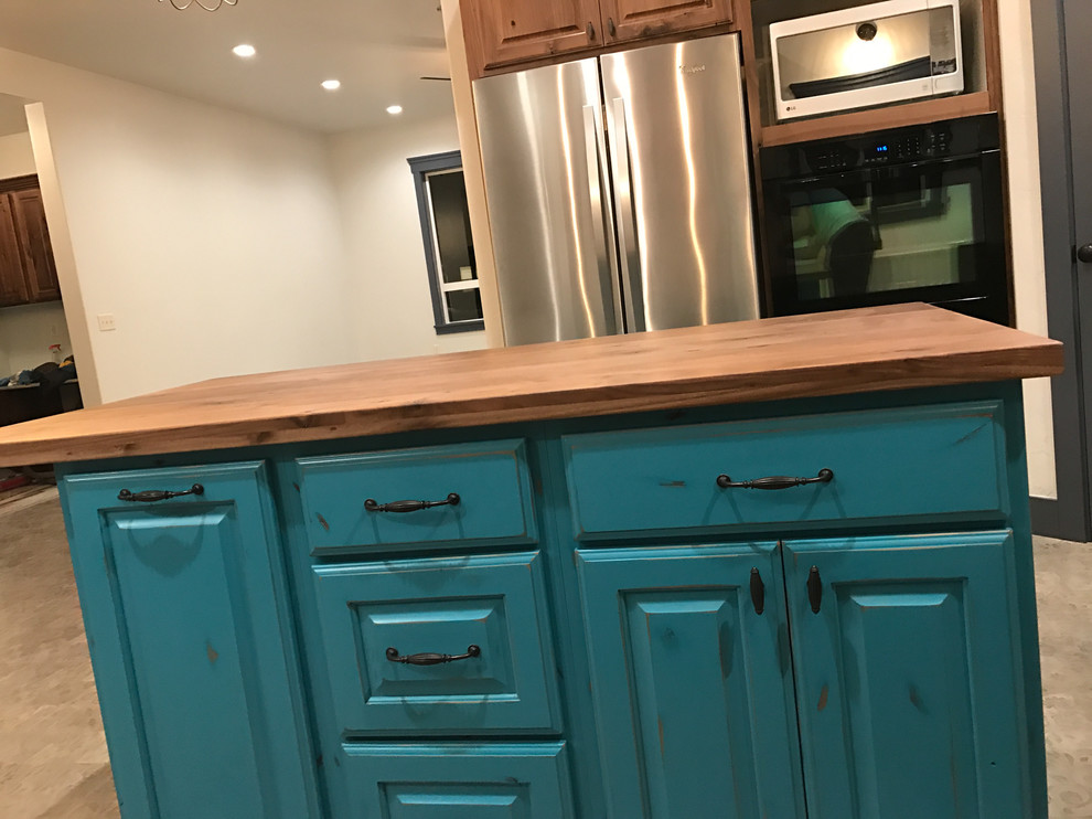 This is an example of a medium sized shabby-chic style l-shaped kitchen/diner in Salt Lake City with raised-panel cabinets, medium wood cabinets, wood worktops, beige splashback, stainless steel appliances, ceramic flooring and an island.