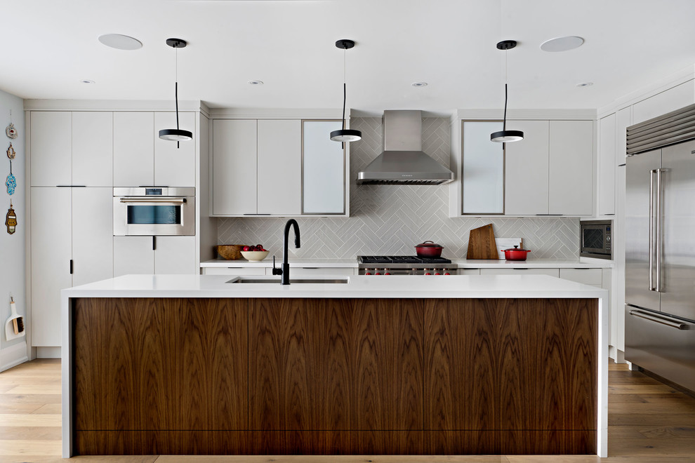 Idéer för ett mellanstort modernt vit kök, med en undermonterad diskho, släta luckor, grå skåp, bänkskiva i kvarts, grått stänkskydd, stänkskydd i keramik, rostfria vitvaror, ljust trägolv, en köksö och brunt golv