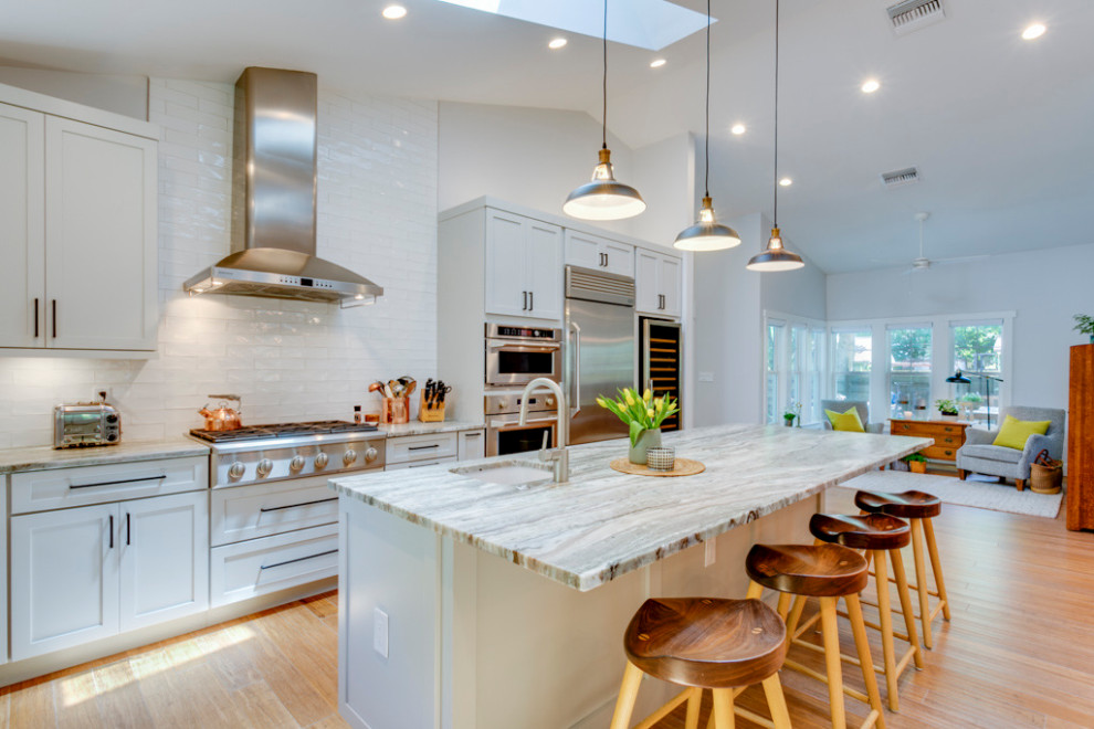 Photo of a large classic l-shaped kitchen/diner in Tampa with a belfast sink, shaker cabinets, grey cabinets, granite worktops, white splashback, metro tiled splashback, stainless steel appliances, bamboo flooring, an island and a vaulted ceiling.