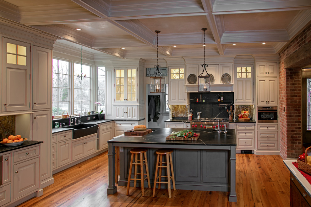 Eat-in kitchen - large farmhouse l-shaped medium tone wood floor eat-in kitchen idea in New York with an integrated sink, beaded inset cabinets, white cabinets, soapstone countertops, black backsplash, stone slab backsplash, paneled appliances and an island
