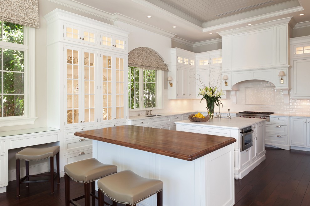 Example of a mid-sized classic l-shaped dark wood floor and brown floor eat-in kitchen design in Tampa with a double-bowl sink, shaker cabinets, white cabinets, granite countertops, white backsplash, subway tile backsplash, white appliances and an island