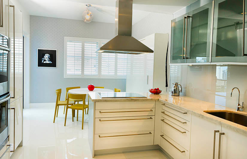 Medium sized modern l-shaped kitchen/diner in Miami with a submerged sink, glass-front cabinets, white cabinets, granite worktops, white splashback, glass sheet splashback, stainless steel appliances, porcelain flooring and an island.