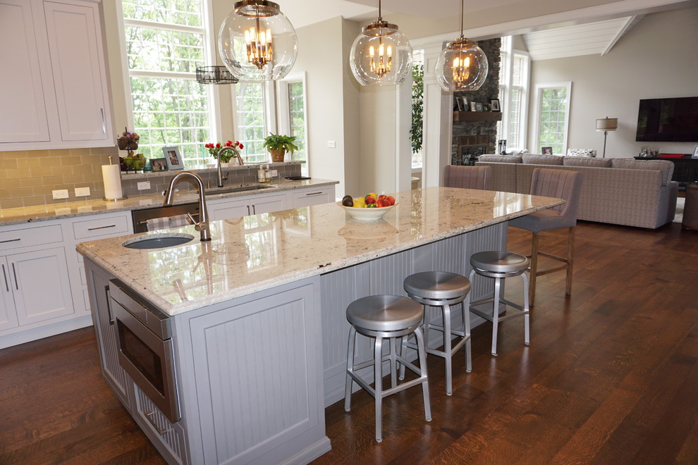 Große Klassische Küche mit Kassettenfronten, weißen Schränken, Granit-Arbeitsplatte, Küchenrückwand in Beige und Kücheninsel in Sonstige