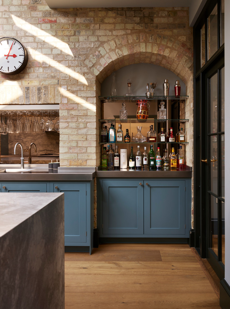 ロンドンにあるラグジュアリーな広いトランジショナルスタイルのおしゃれなキッチン (アンダーカウンターシンク、落し込みパネル扉のキャビネット、青いキャビネット、人工大理石カウンター、グレーのキッチンパネル、石スラブのキッチンパネル、シルバーの調理設備、無垢フローリング、茶色い床) の写真
