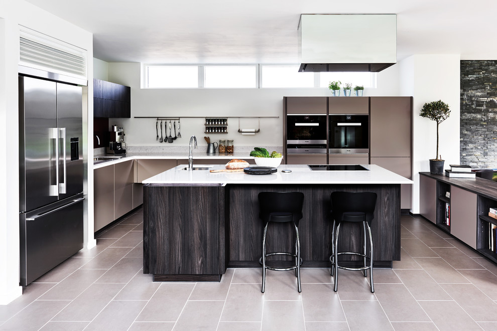 Moderne Küche mit Unterbauwaschbecken, flächenbündigen Schrankfronten, braunen Schränken, Küchengeräten aus Edelstahl, Kücheninsel, beigem Boden und weißer Arbeitsplatte in Wiltshire