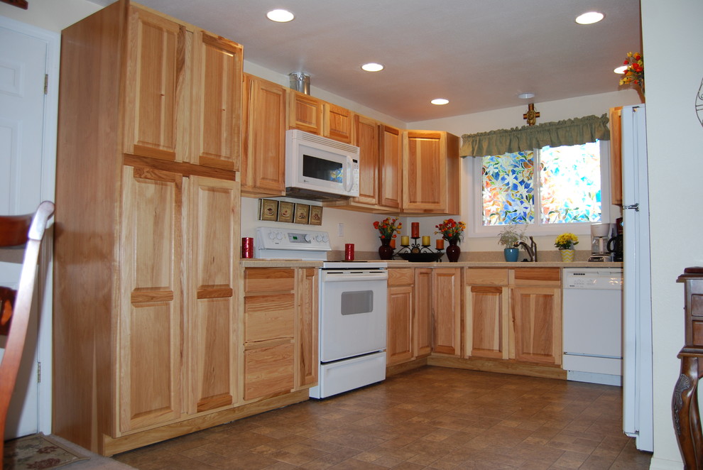 Klassisk inredning av ett avskilt, mellanstort u-kök, med luckor med upphöjd panel, skåp i ljust trä, träbänkskiva, vita vitvaror och vinylgolv
