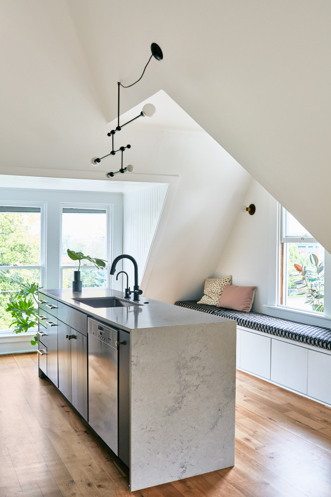 Moderne Küche mit Unterbauwaschbecken, flächenbündigen Schrankfronten, schwarzen Schränken, braunem Holzboden, Kücheninsel, braunem Boden und grauer Arbeitsplatte in Portland