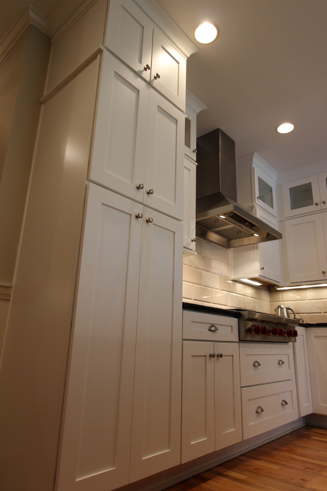 Inspiration for a mid-sized contemporary l-shaped medium tone wood floor eat-in kitchen remodel in Atlanta with a single-bowl sink, shaker cabinets, white cabinets, granite countertops, beige backsplash, subway tile backsplash, stainless steel appliances and an island